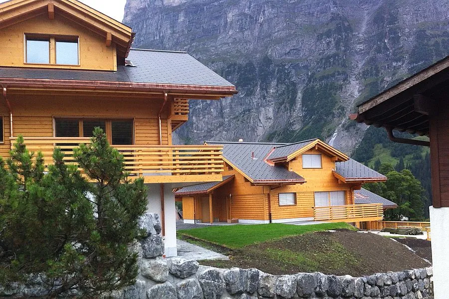 Zwei Holzchalets in Grindelwald vor einer steilen Felswand