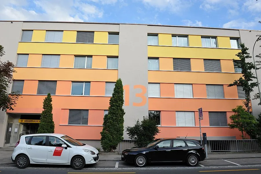 Mehrfamilienhaus mit verputzter Aussenwärmedämmung in gelben, orangen und lachsfarbenen Bändern