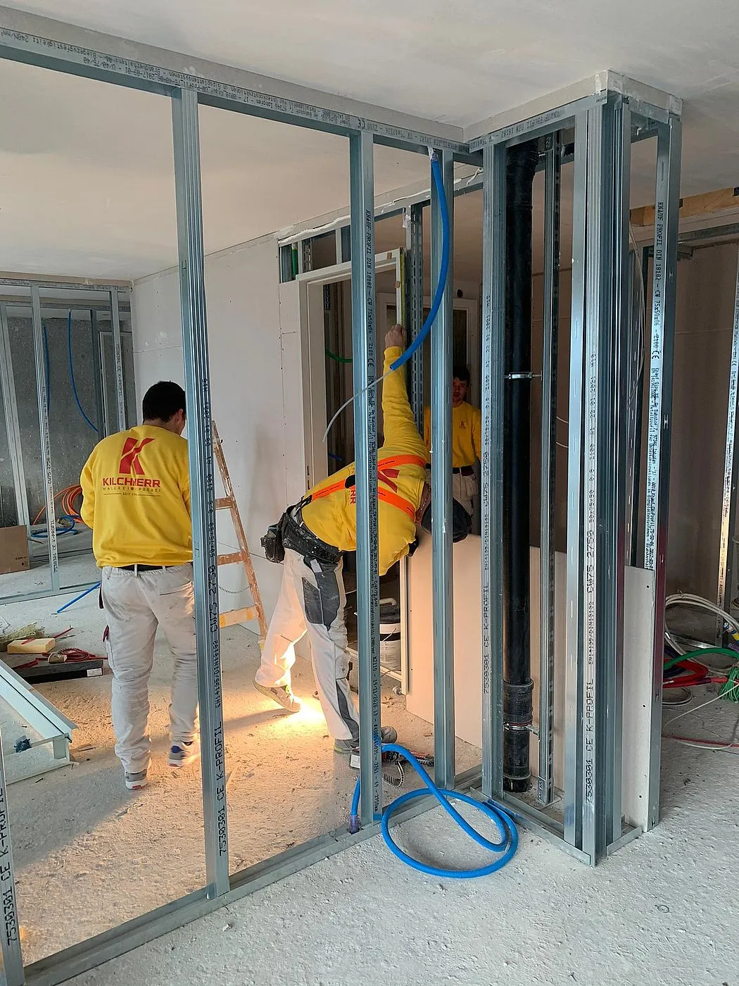 Mitarbeitende in gelben Shirts stellen im Bärentower Metallständer für Trockenbauwände