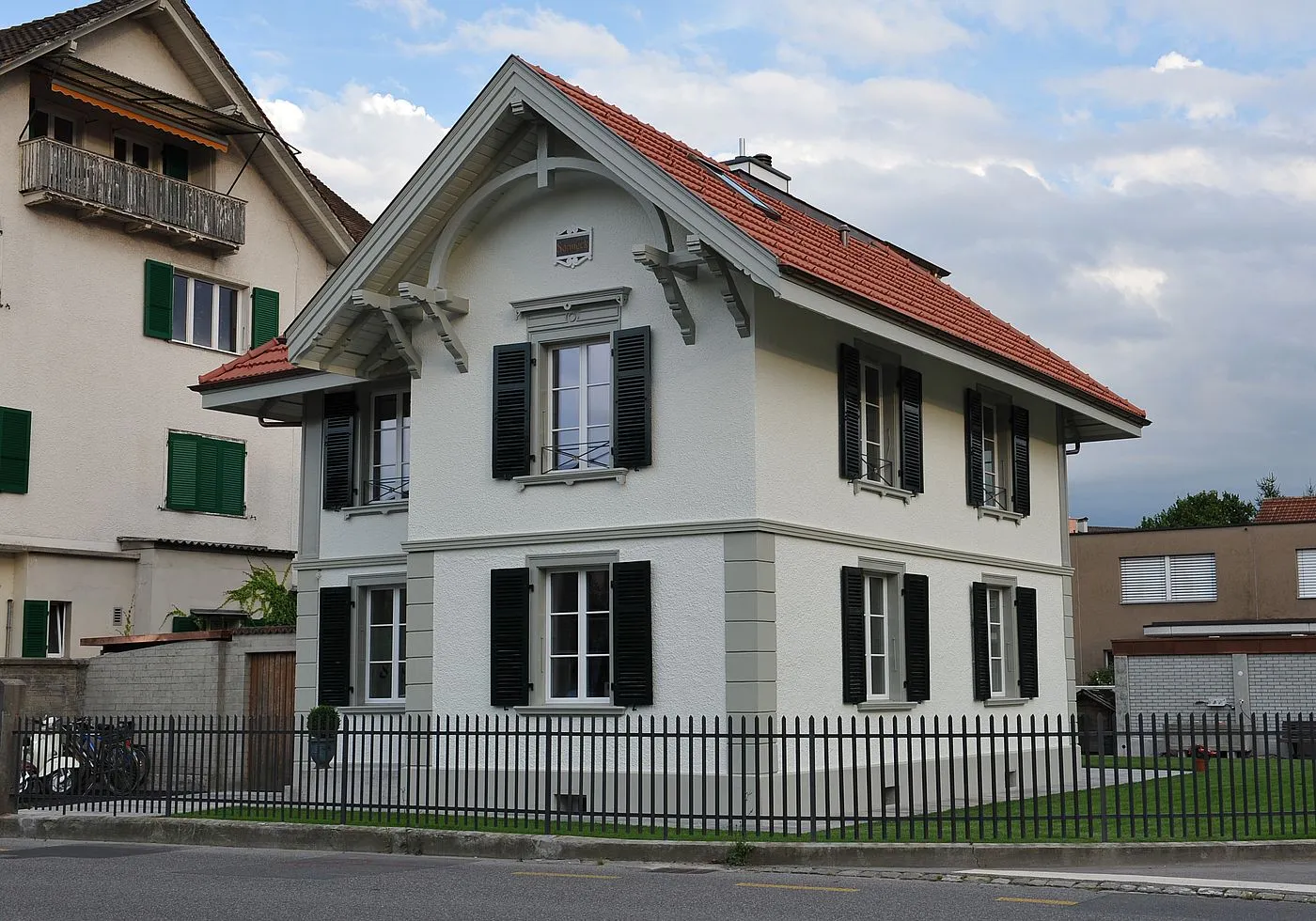 Renoviertes Einfamilienhaus in Thun mit weisser Fassade, dunkelgrünen Fensterläden und rotem Ziegeldach