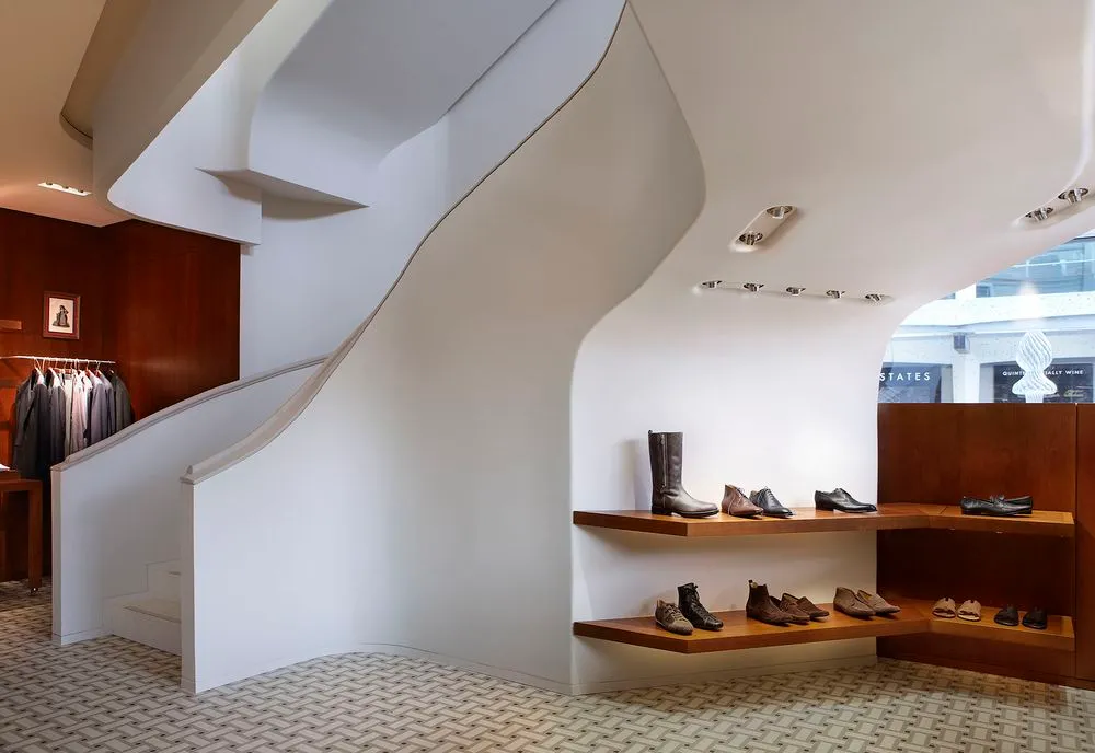 Fertiggestellte, weiss geschwungene Treppe im Hermes-Geschäft in Genf mit Schuhregalen aus Holz