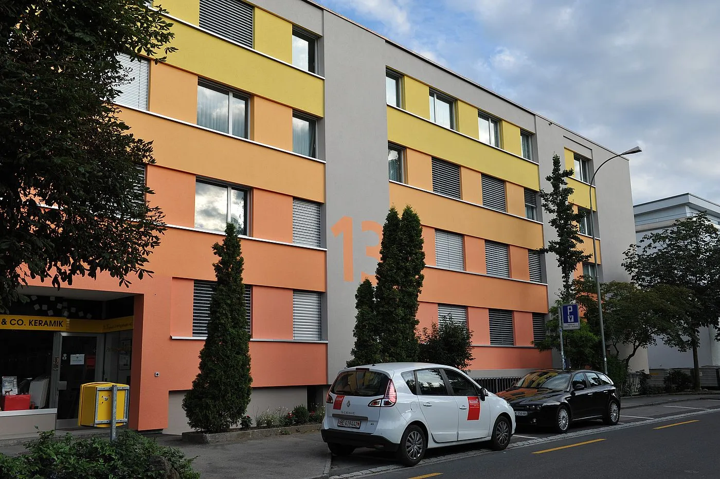Mehrfamilienhaus in Thun mit verputzter Aussenwärmedämmung in gelben, orangen und lachsfarbenen Bändern